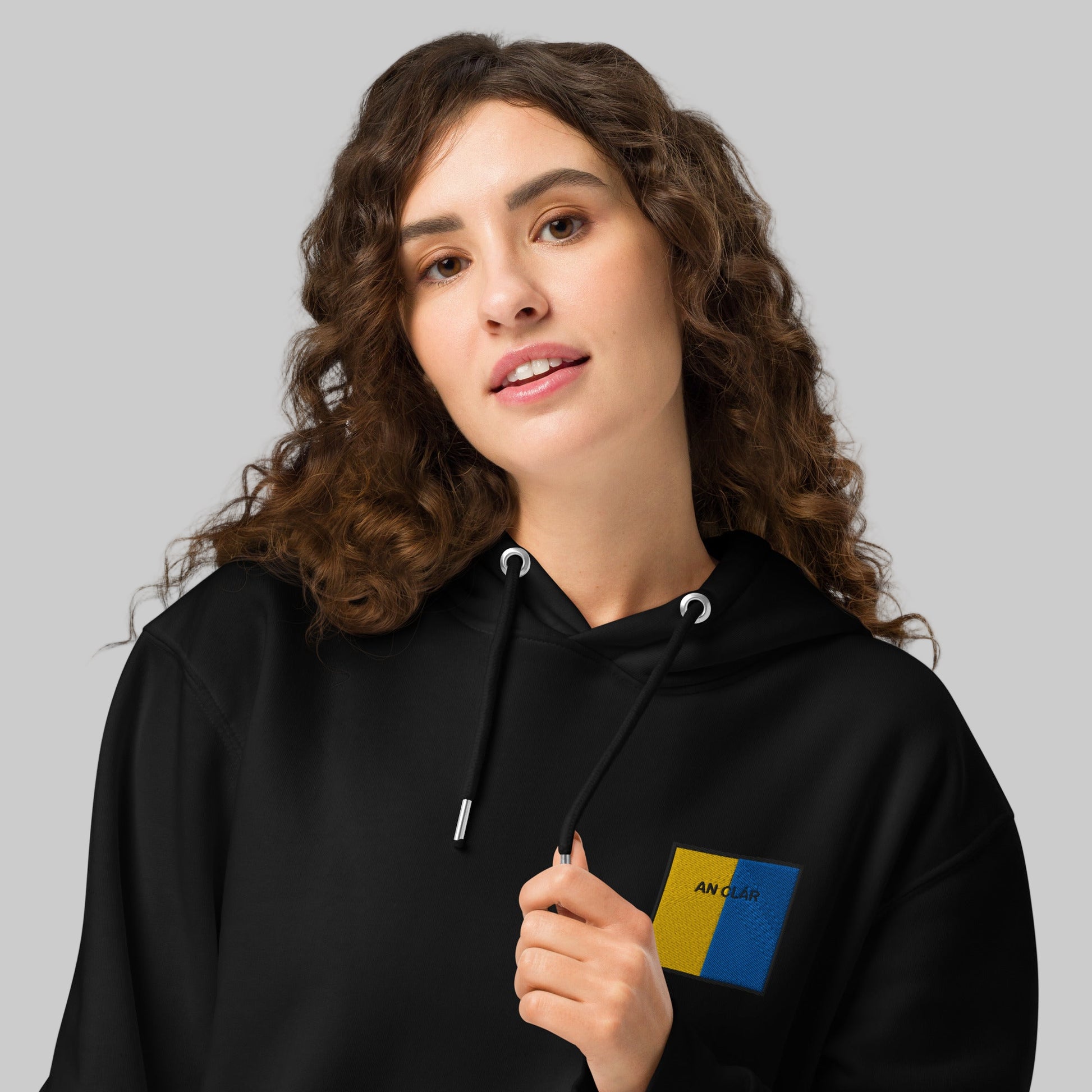 Woman wearing a black hoodie with an Clár emblem