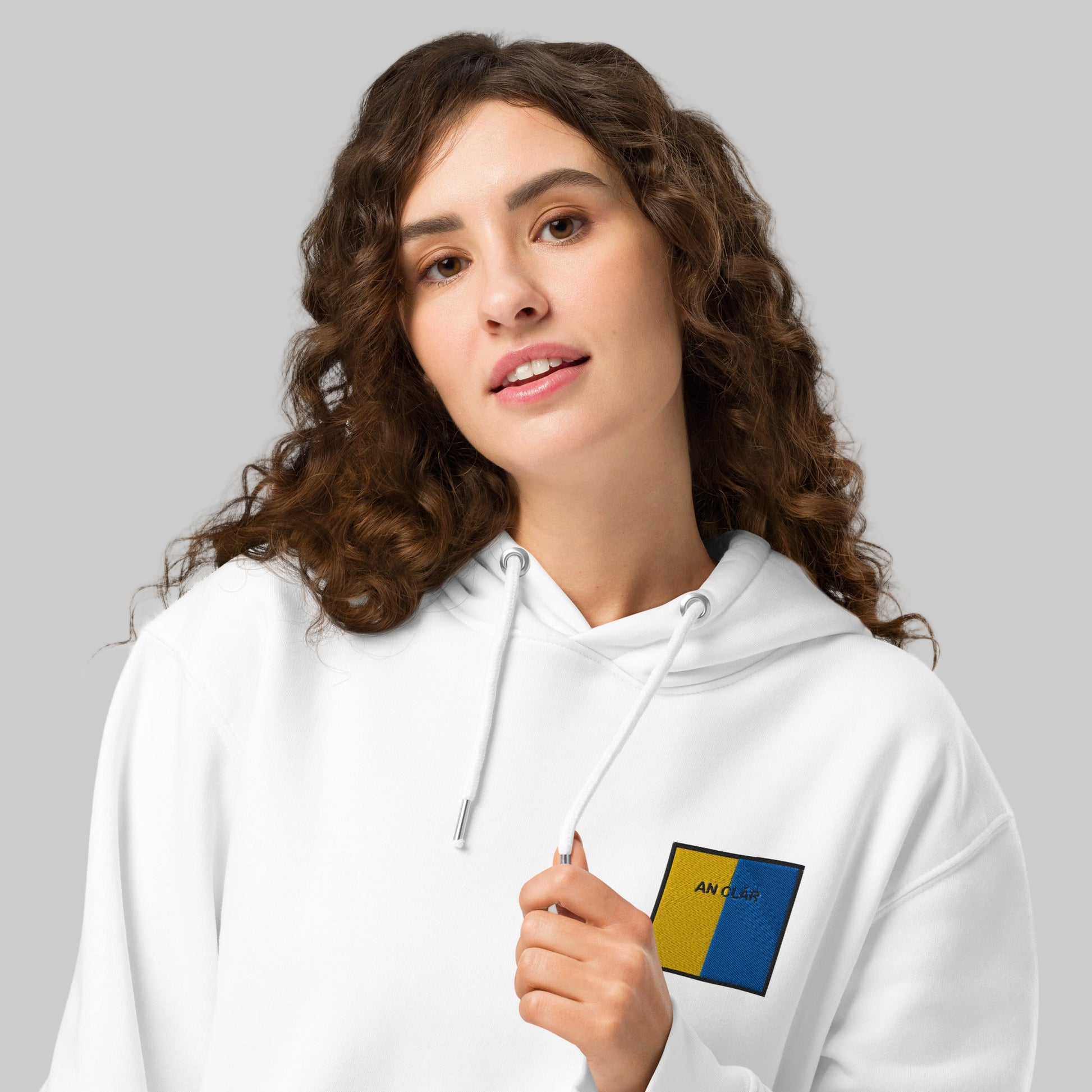 Woman wearing a white hoodie with an embroidered an Clár emblem 