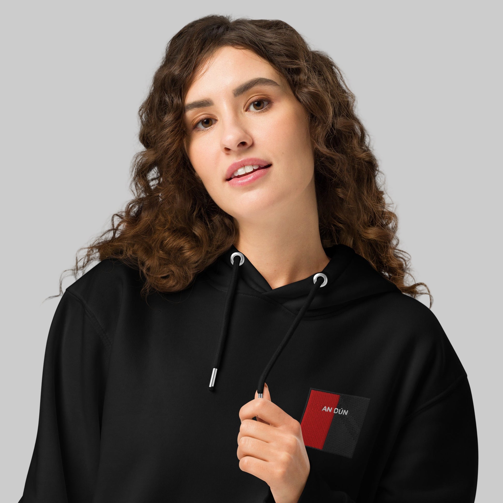 Woman wearing a black hoodie with embroidered an DÚN emblem 