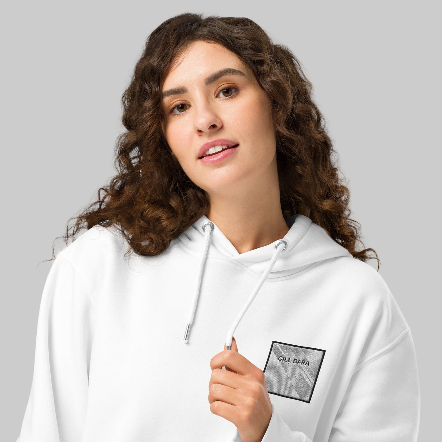 Woman wearing a white hoodie with Cill Dara enblem 