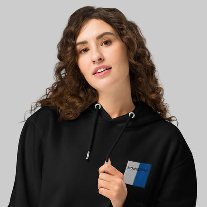 Woman wearing a black hoodie with a Monaghan emblem 