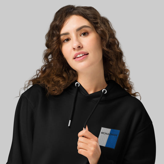 Woman wearing a black hoodie with a Monaghan emblem 