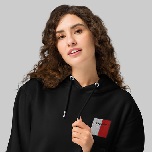 Woman wearing a black hoodie with a Tyrone embroidered emblem

