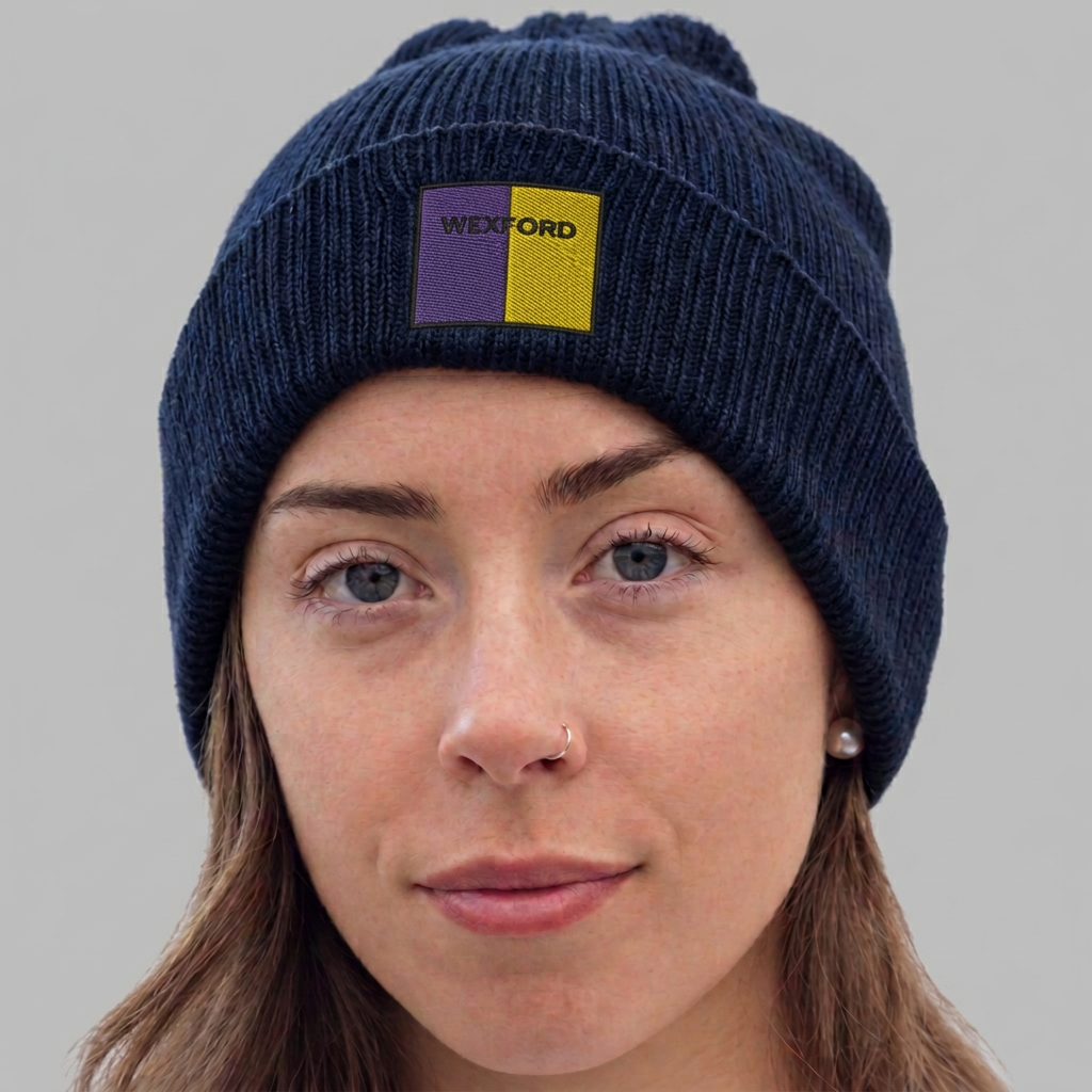 A close-up of a woman wearing a navy blue ribbed knit beanie with a purple and yellow front patch that reads 'WEXFORD'.
